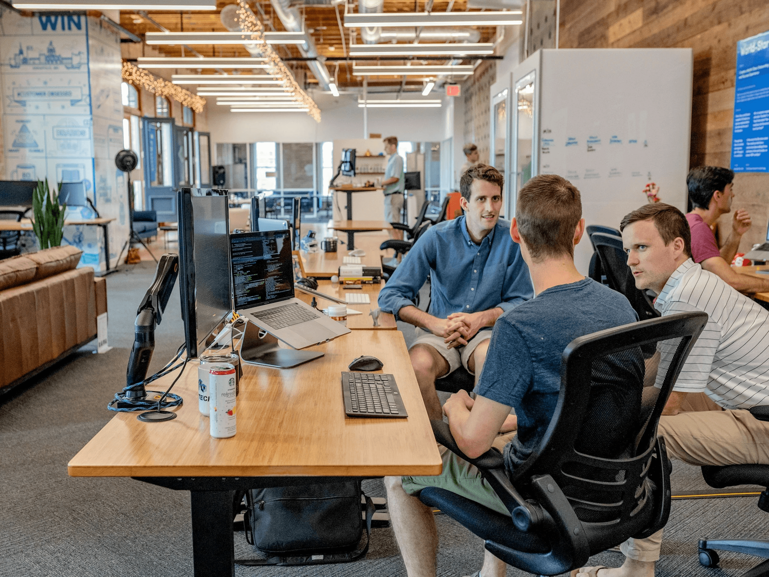 Colleagues discussing work around desks in an open office
